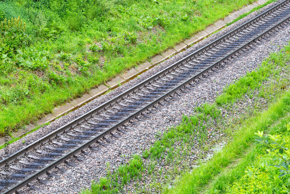 The rails go from left to right up, gravel and grass are placed on both sides. The rails go from left to right up, gravel and grass are placed on both sides.