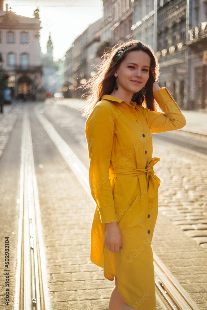 Fototapeta premium Fashionable positive girl in summer outfit walk on old city street