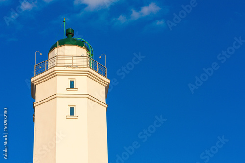 A beautiful white lighthouse against a blue sky.