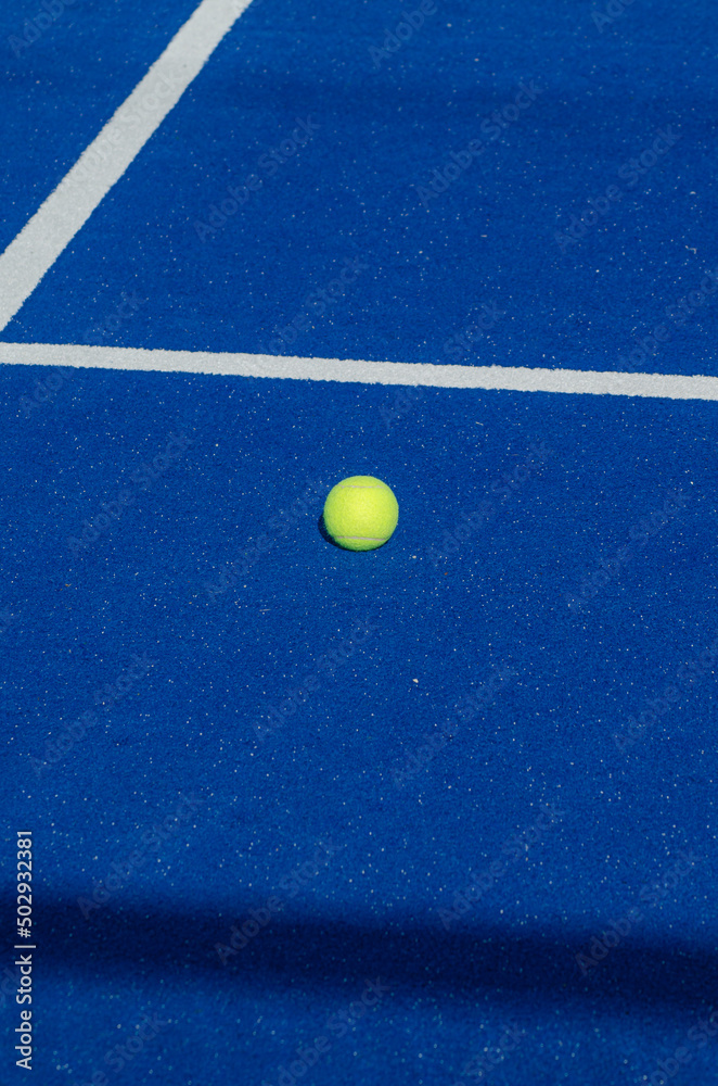 blue paddle tennis court, a solitary ball close to the baseline