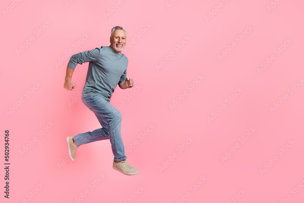 Full length body size view of attractive cheery motivated grey-haired man jumping running isolated over pink pastel color background