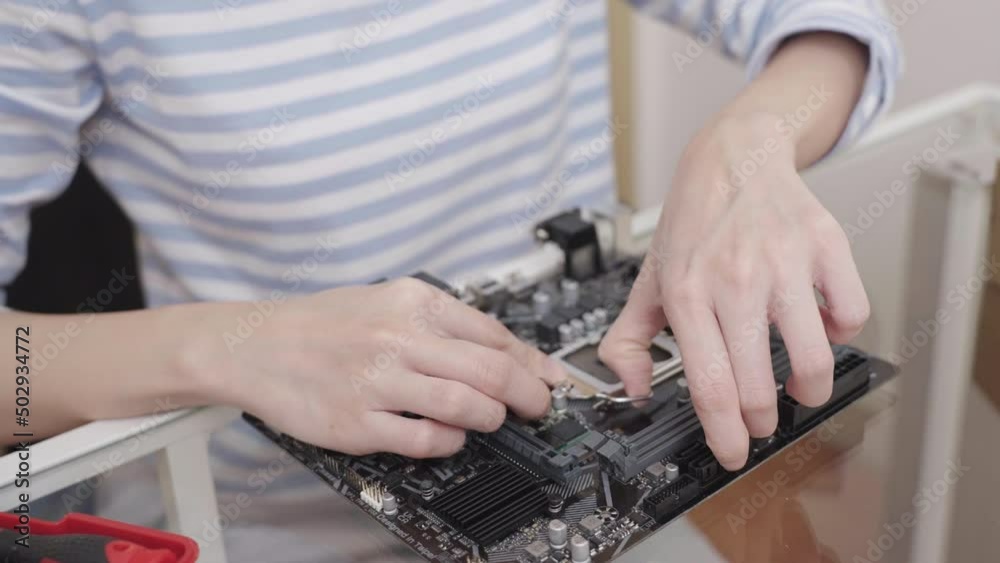 Close-up, Hand of woman opening a CPU socket on the computer motherboard. (installing or repairing). Close-up, Hand of woman opening a CPU socket on the computer motherboard. (installing or repairing).