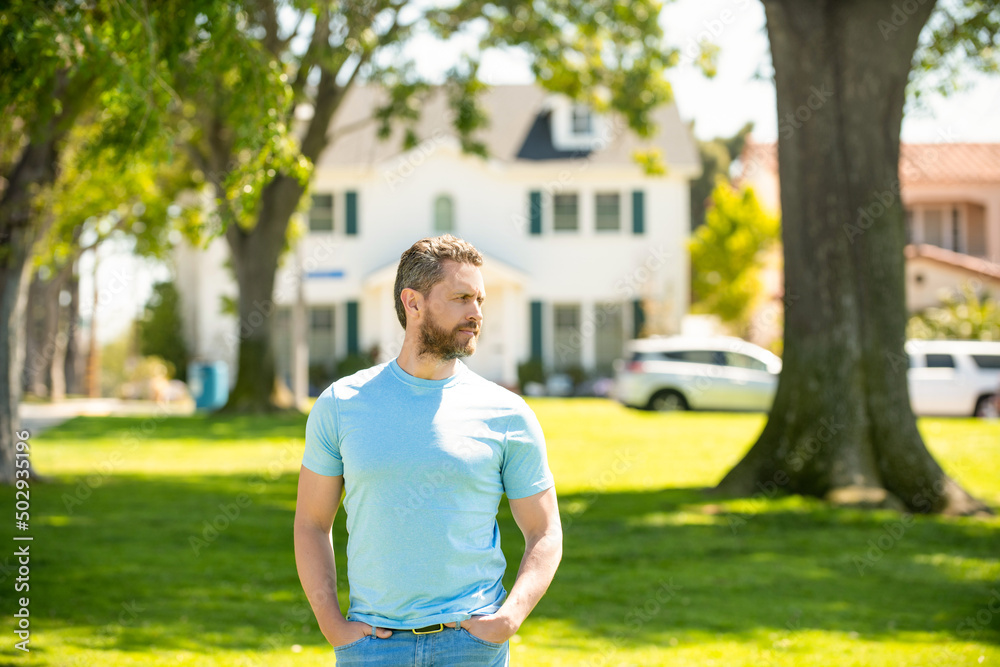 serious unshaven guy standing near new house, real estate serious unshaven guy standing near new house, real estate
