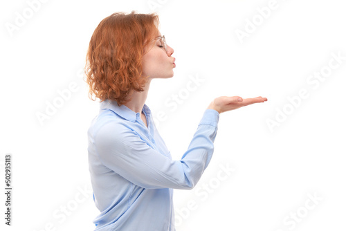 Attractive redhead girl promoter in blue business shirt holding something in hand demonstrating empty space with excited face isolated on white background