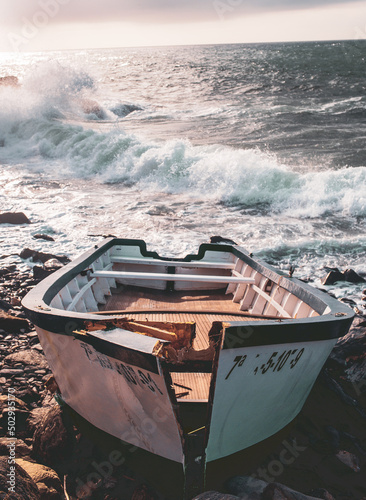 Boats in the beach on sunset and sunrise, foggy, stormy wheater, ocean water drops in the air and cliffs in the background photo