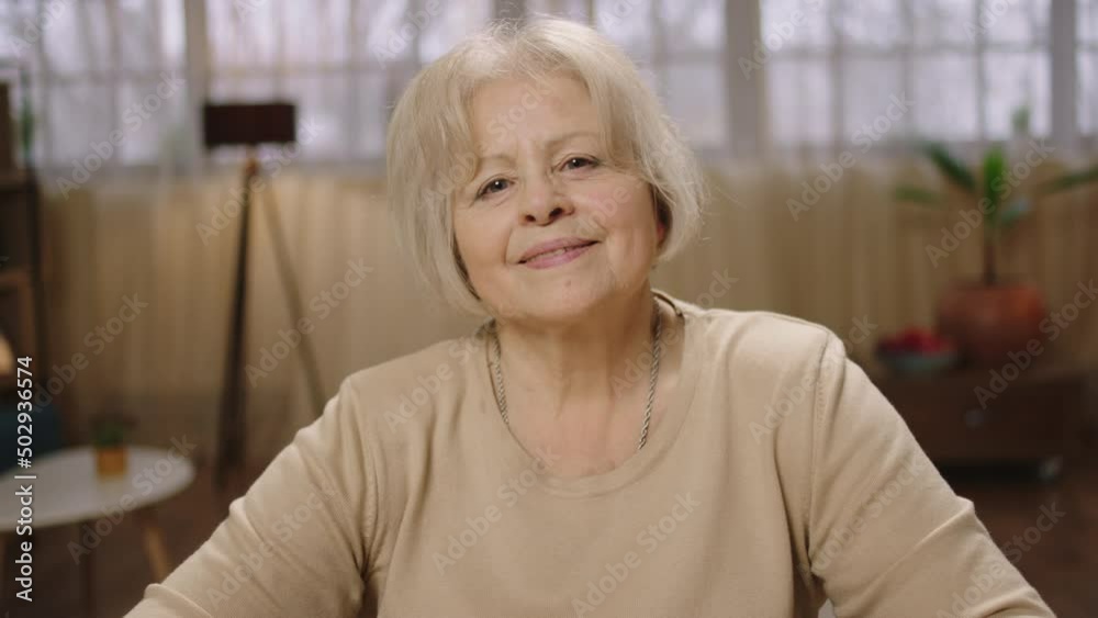 Looking straight to the camera making portrait of a beautiful old woman at home she smiling cute Looking straight to the camera making portrait of a beautiful old woman at home she smiling cute