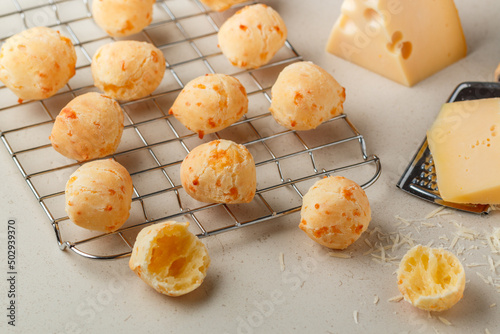 Freshly baked homemade cheese buns on a baking rack on a light background close-up. Brazilian cheese bread. A gourmet snack. Delicious pastries. Selective focus