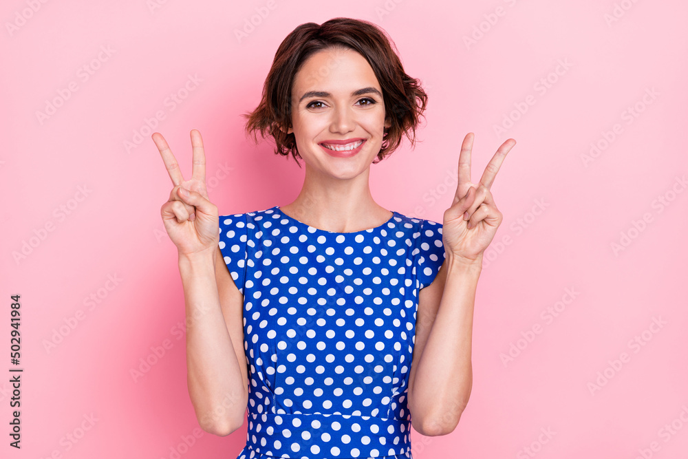 Photo of pretty cheerful young woman showing v-sign gesture saying hi hello isolated on pink color background Photo of pretty cheerful young woman showing v-sign gesture saying hi hello isolated on pink color background