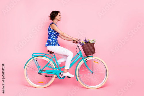 Full body photo of optimistic young lady ride bicycle wear blouse pants shoes isolated on pink background © deagreez