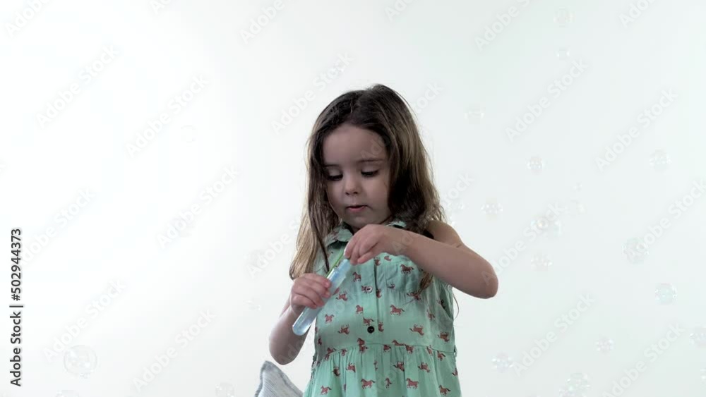 Cute young girl playing with soap bubbles. Portrait. White background Cute young girl playing with soap bubbles. Portrait. White background