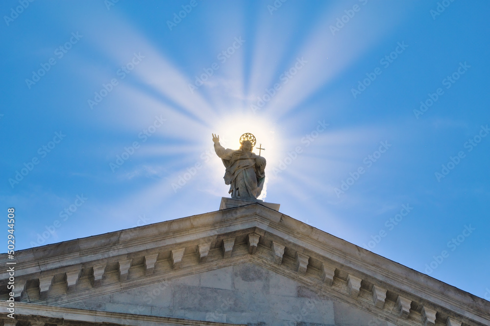 Obraz premium Statue of Jesus Christ surrounded by sun rays against clear blue sky