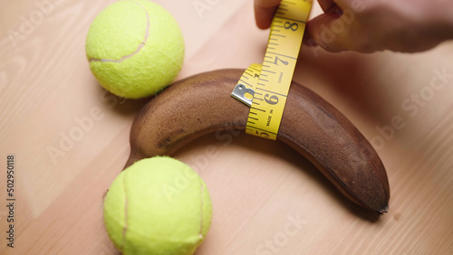 Person with measuring tape measure manhood girth of black banana with balls
