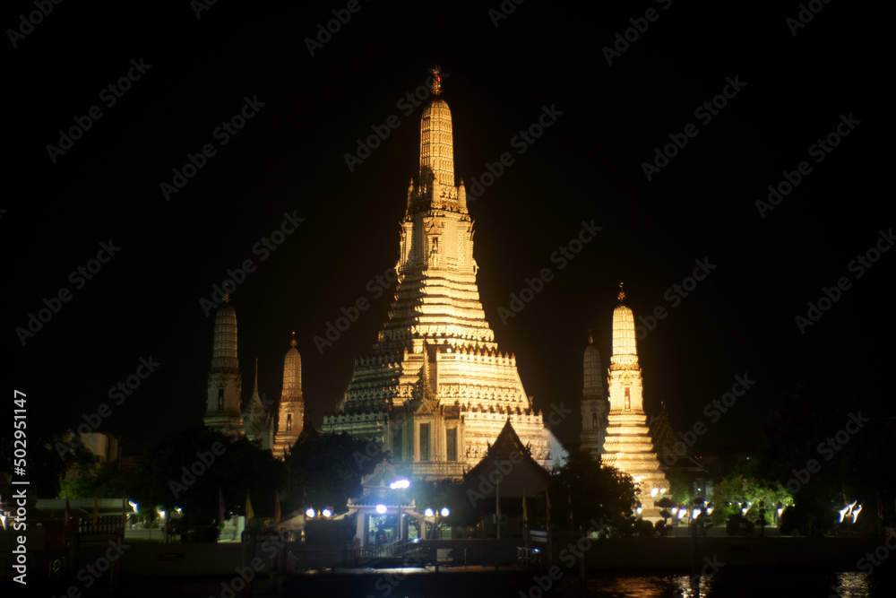 Ancient temple Wat Arun Temple under night sky at Chaophraya riverside ,Bangkok ,Thailand .This temple is public place and famous landmark tourist attraction in Thailand