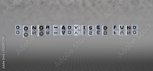 donor advised fund word or concept represented by black and white letter cubes on a grey horizon background stretching to infinity