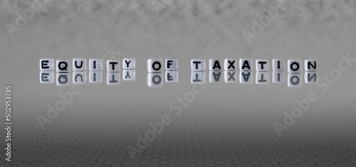 equity of taxation word or concept represented by black and white letter cubes on a grey horizon background stretching to infinity