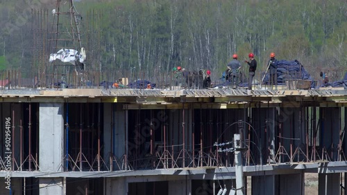 Large construction site with buildings under construction and multi-storey residential homes timelapse. Workers in action on blue sky background. Housing renovation concept.