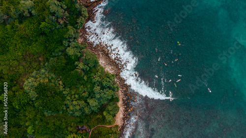 View of the ocean and coast from a drone, surfers with boards in the water waiting for the waves,
