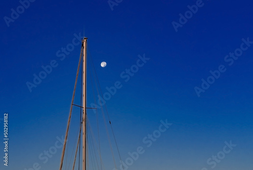 Full Moon and Sailing yacht mast on twilight dark blue sky