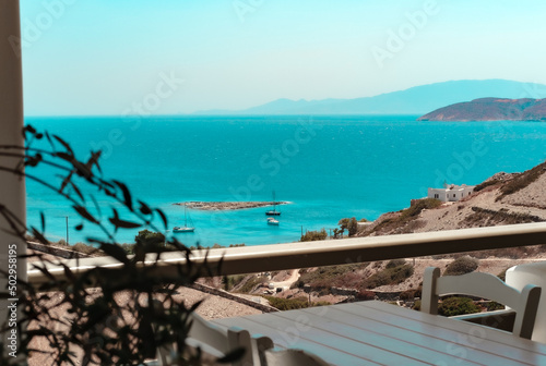 Schinoussa island seascape view from taverna terrace, sailing yachts on anchorage, small islet, blue horizon photo