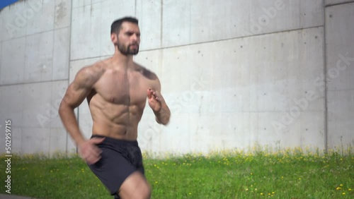 Handheld shot of athletic man doing skip up exercise outdoors