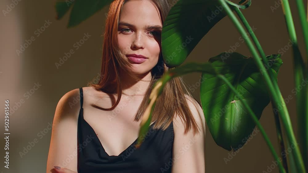 Lovely caucasian young girl with fresh healthy glowing skin posing near tropical green leaves enjoy wind. ProRes