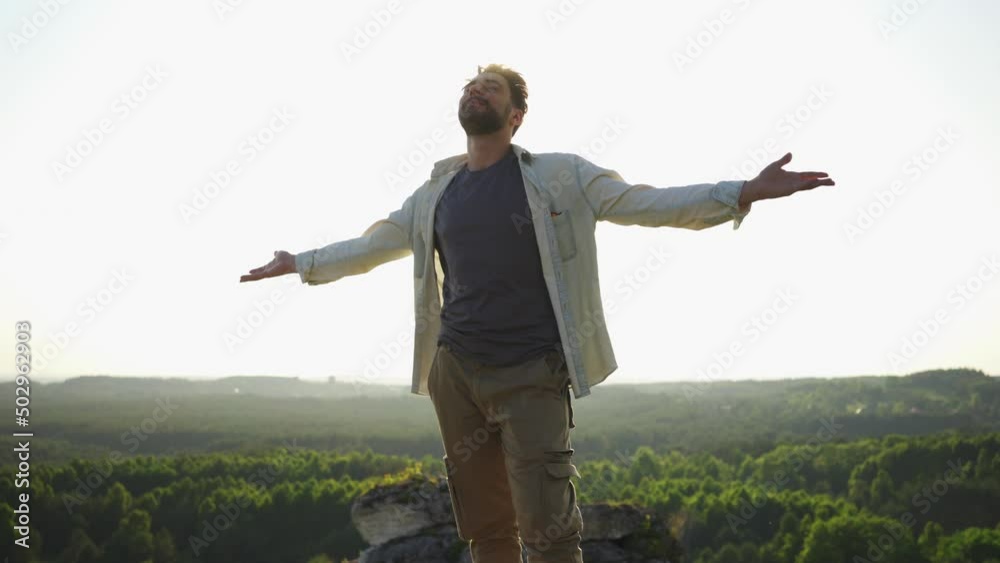 Handsome young man with open arms enjoying summer hike in mountains Handsome young man with open arms enjoying summer hike in mountains