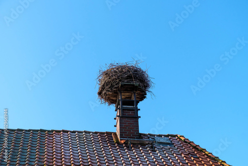 Foto Stork nest on a chimney on a roof against a blue sky