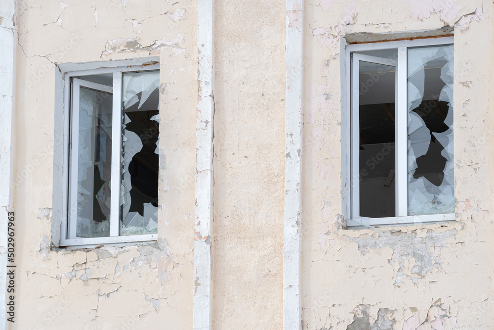 Two windows on the facade of the house with blown-out windows
