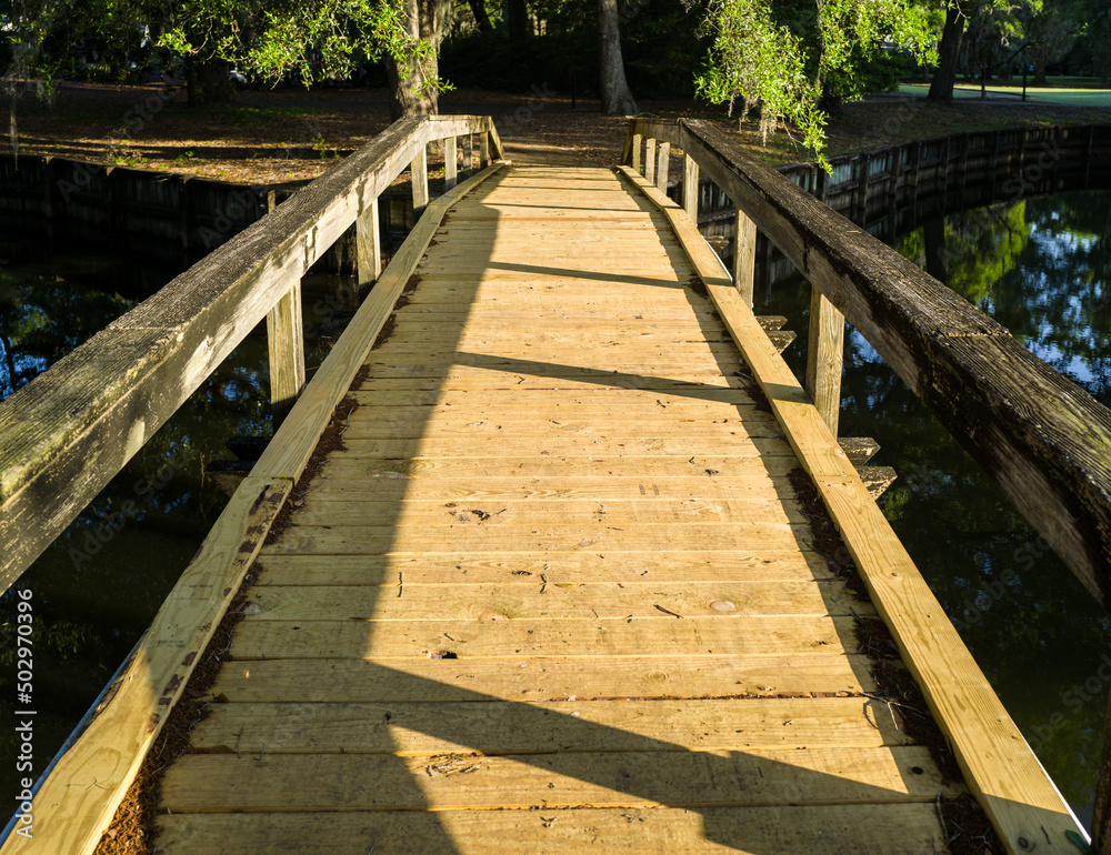 Empty wooden boardwalk footbridge over the pond