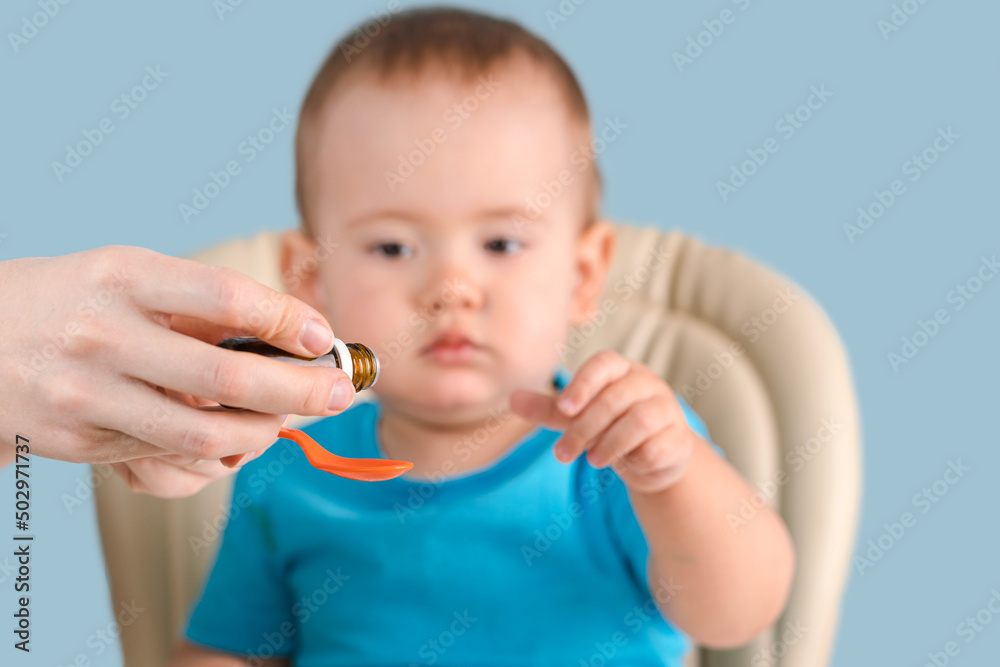 Mom pours syrup with medicine into a spoon, toddler reaches for a spoon with medicine. Mom pours syrup with medicine into a spoon, toddler reaches for a spoon with medicine.