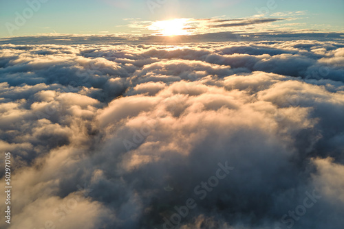 Fototapeta Naklejka Na Ścianę i Meble -  Aerial view from airplane window at high altitude of dense puffy cumulus clouds flying in evening