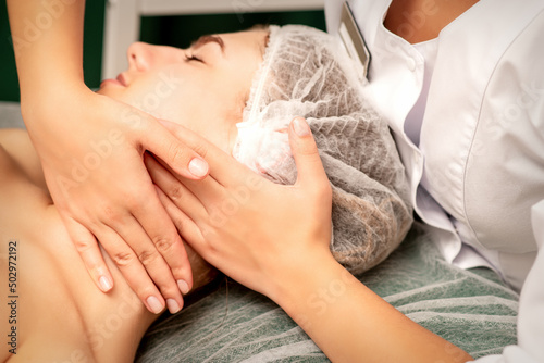 Facial massage. Hands of a masseur massaging neck of a young caucasian woman in a spa salon, the concept of health massage