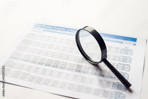 Business concept. Magnifying glass on paper background with financial data