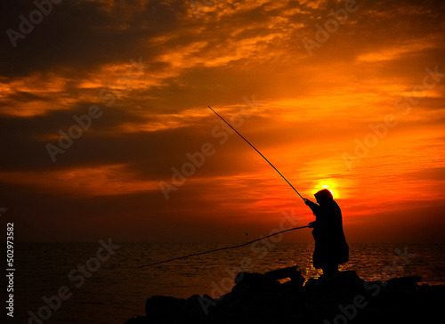 fisherman with a fishing rod at sunrise