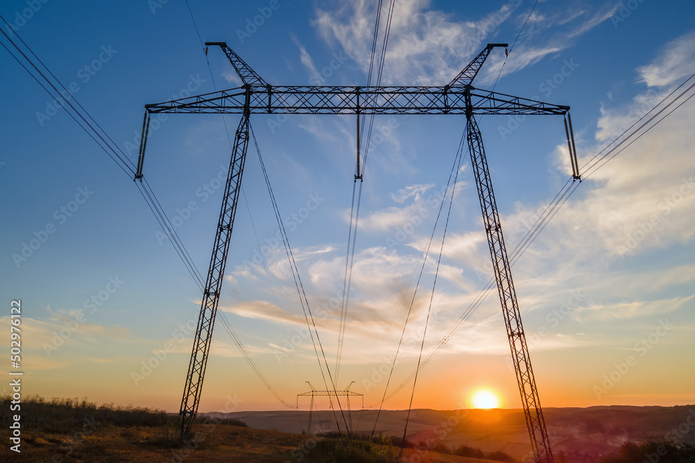 High voltage tower with electric power lines at sunset. Transmission of electricity