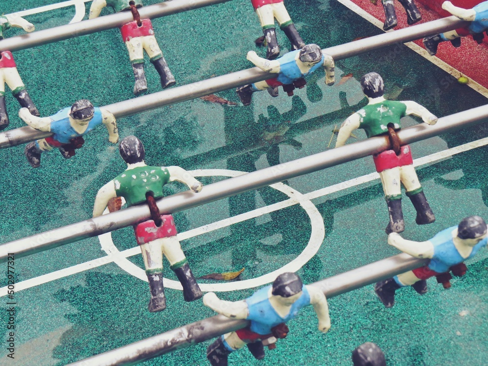 Primer plano de un futbolín abandonado. Primer plano de las figuras de los jugadores y barras metálicas que los sujetan del centro de la mesa de juego.