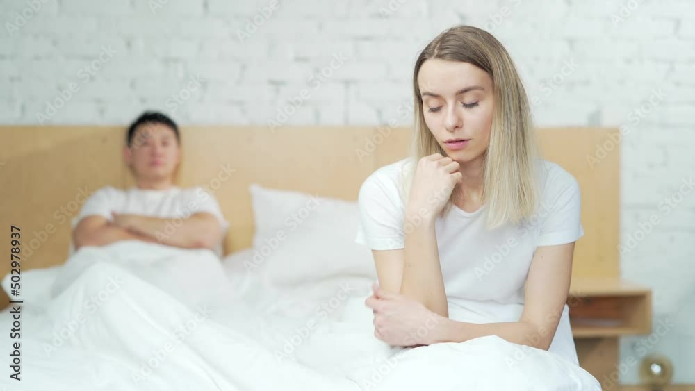 Young unhappy family couple problem in bed. Upset young asian man sitting at home after quarrel. husband and wife are difficult in a relationship. Divorce, marriage, conflict, crisis, love concept Young unhappy family couple problem in bed. Upset young asian man sitting at home after quarrel. husband and wife are difficult in a relationship. Divorce, marriage, conflict, crisis, love concept