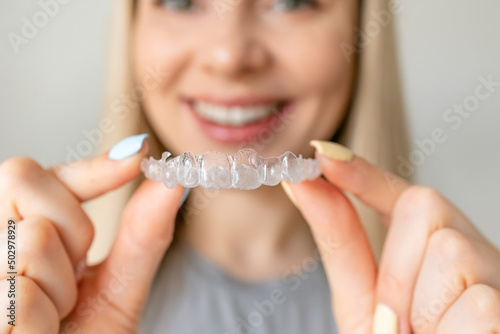 Close up of woman hold transparent aligners. Taking care of teeth. Orthodontic treatment for straightening and whitening teeth.