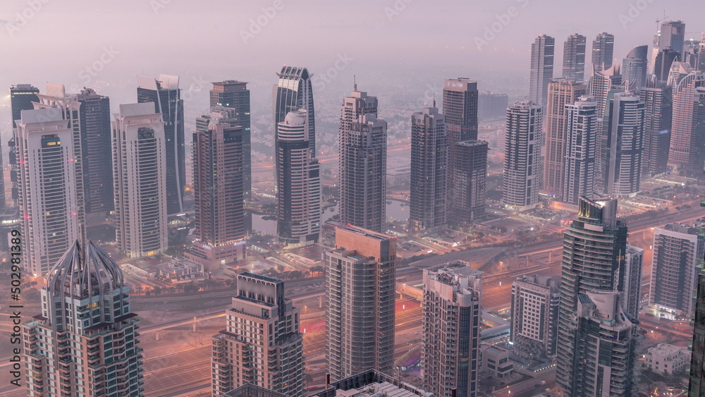 Obraz premium JLT skyscrapers and marina towers near Sheikh Zayed Road aerial night to day timelapse. Residential buildings