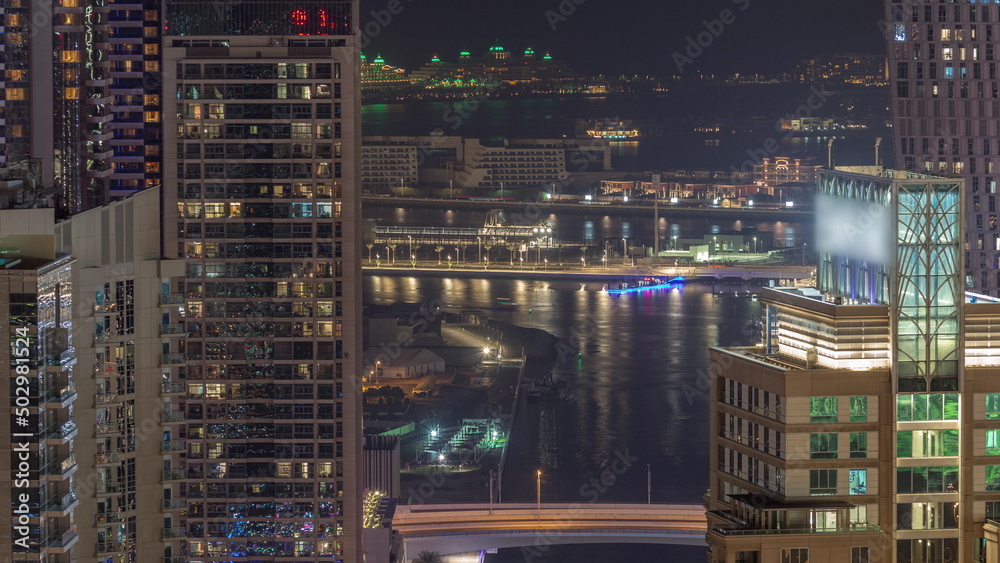 Promenade and canal in Dubai Marina with luxury skyscrapers around night timelapse, United Arab Emirates