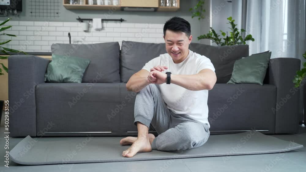 sporty man using fitness smart watch at home. Young male watching a smartwatch training data app while exercising before, after workout watch results tracker to heart beat, pulse, wearable application sporty man using fitness smart watch at home. Young male watching a smartwatch training data app while exercising before, after workout watch results tracker to heart beat, pulse, wearable application