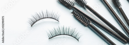 Overhead eyelashes and brushes on blue background. Makeup of female eyes. Eyelash extension. Piece care. Banner.