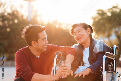 Portrait of smiling young Asian man enjoying sweet tender time outdoor with older senior mother.