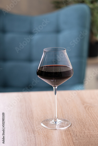 A glass of red wine on a beige light wooden table in a restaurant