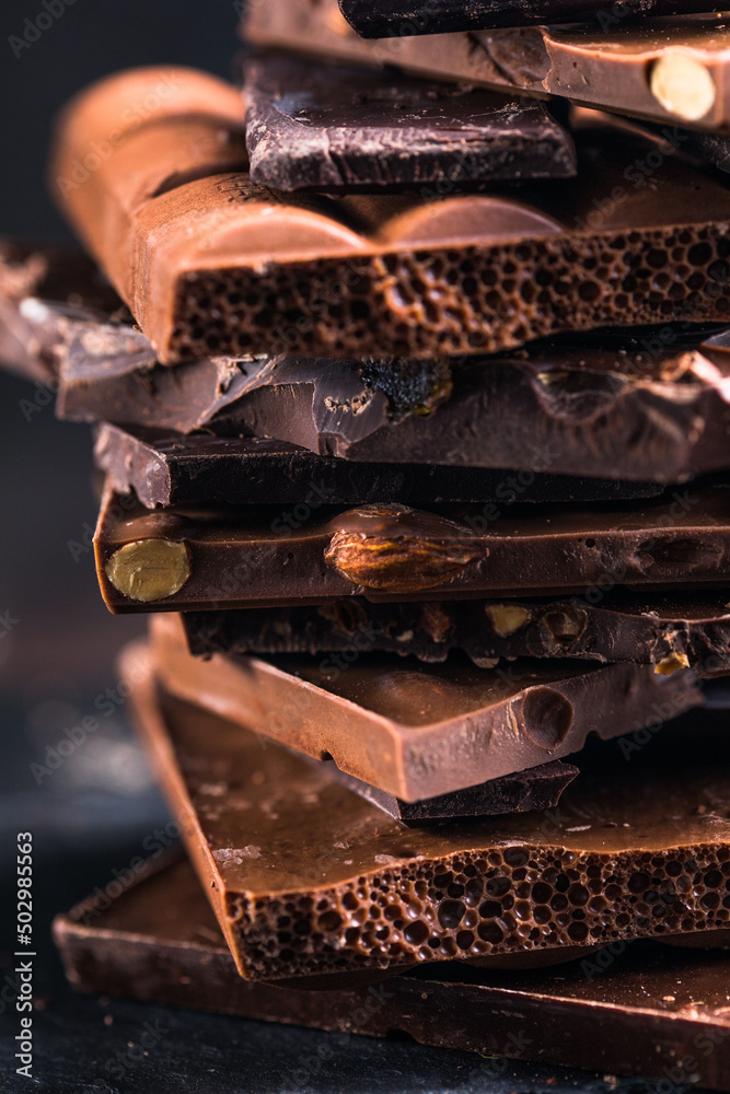 Bar of Chocolate tower pieces. Hazelnut and almond dark chunks of broken chocolate. Sweet food photo concept.