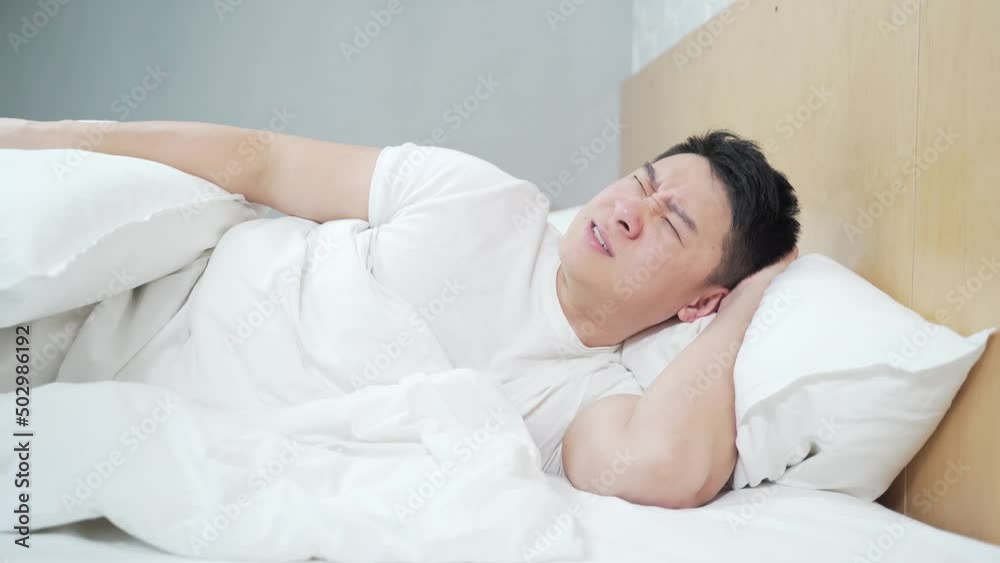 problem of sound insulation and thin walls in apartment House Asian man in Bed Tries To Rest, Irritated By Noisy Neighbors. Insomnia, Repair Work at the Neighbors. The Concept of Neighborhood problem of sound insulation and thin walls in apartment House Asian man in Bed Tries To Rest, Irritated By Noisy Neighbors. Insomnia, Repair Work at the Neighbors. The Concept of Neighborhood