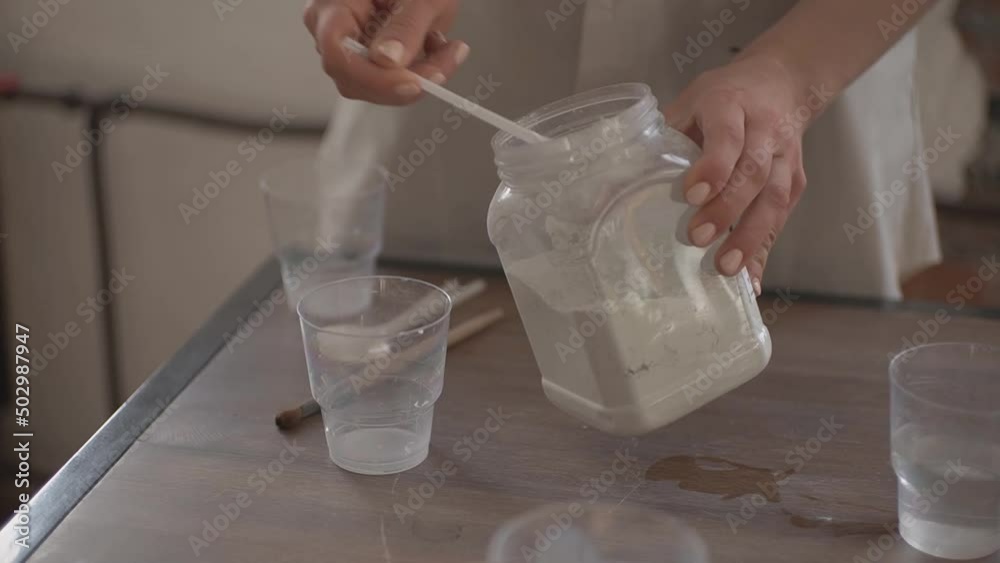 the girl prepares a solution to cover the clay product the girl prepares a solution to cover the clay product