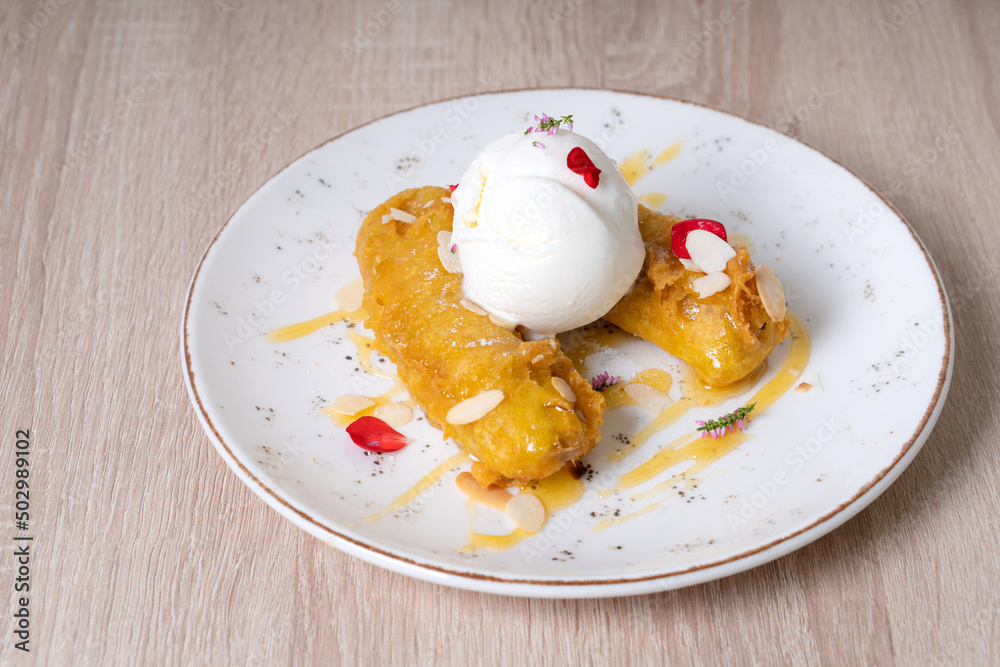 Fried bananas with scoops of ice cream on a white plate Fried bananas with scoops of ice cream on a white plate