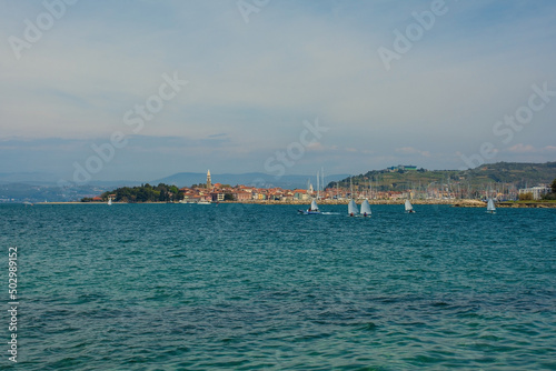The historic town of Izola on the Adriatic coast of Slovenia. A sailing school practices in the foreground right 