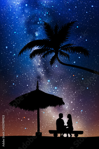 Lovers under straw umbrella. Couple on beach at night. Summer vacation